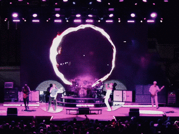 311 on stage under purple light with a glowing ring backdrop