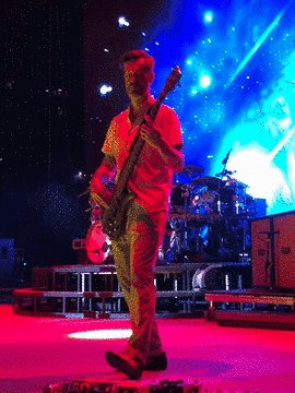 311 bassist playing on stage under red and blue lights