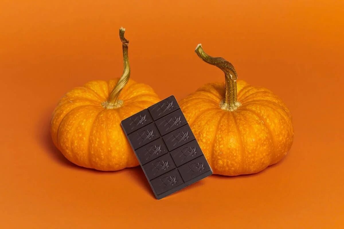 Bhang chocolate bar between two small pumpkins on orange