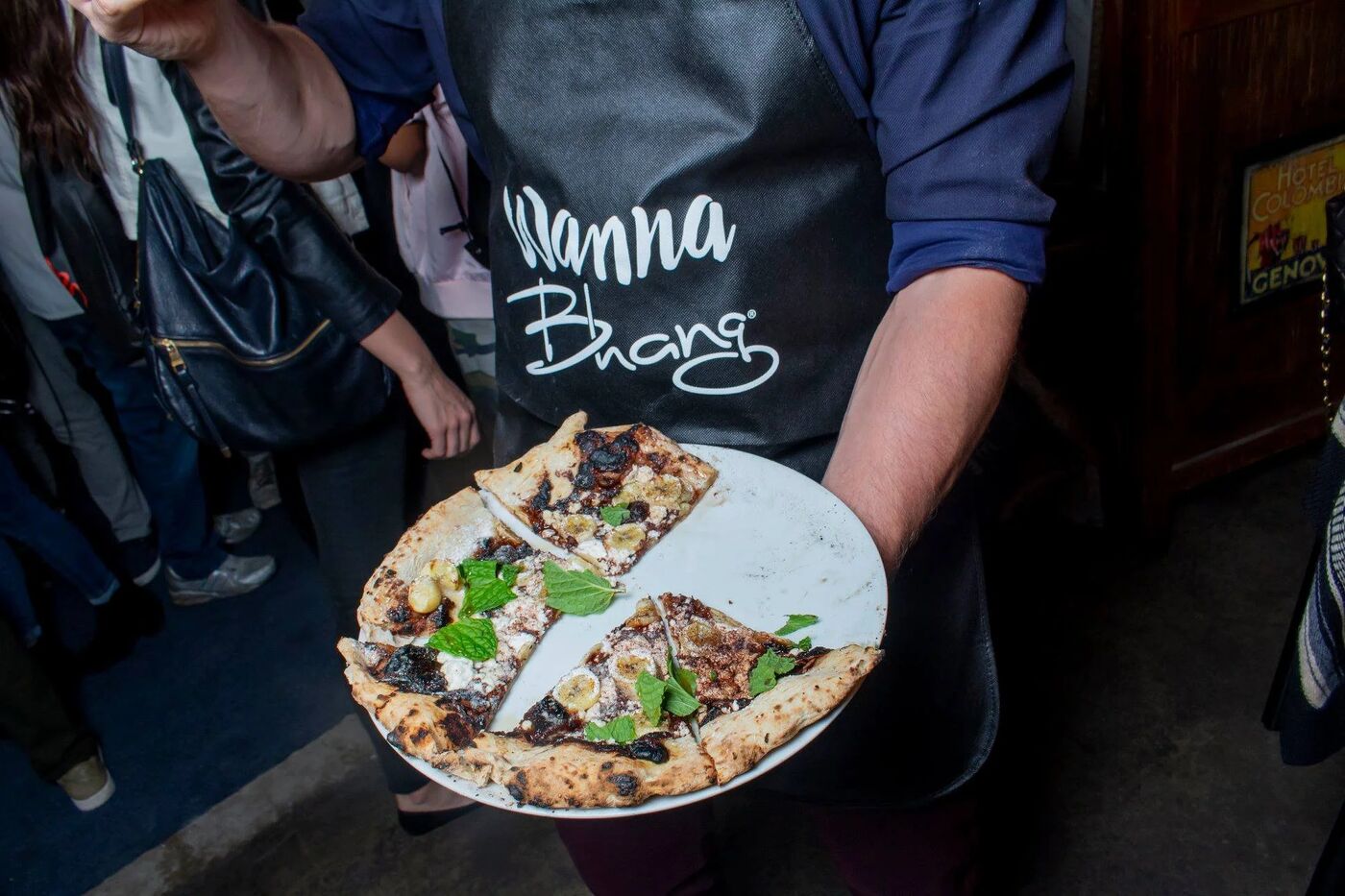 Chef in a Wanna Bhang apron holding a plate of flatbread slices