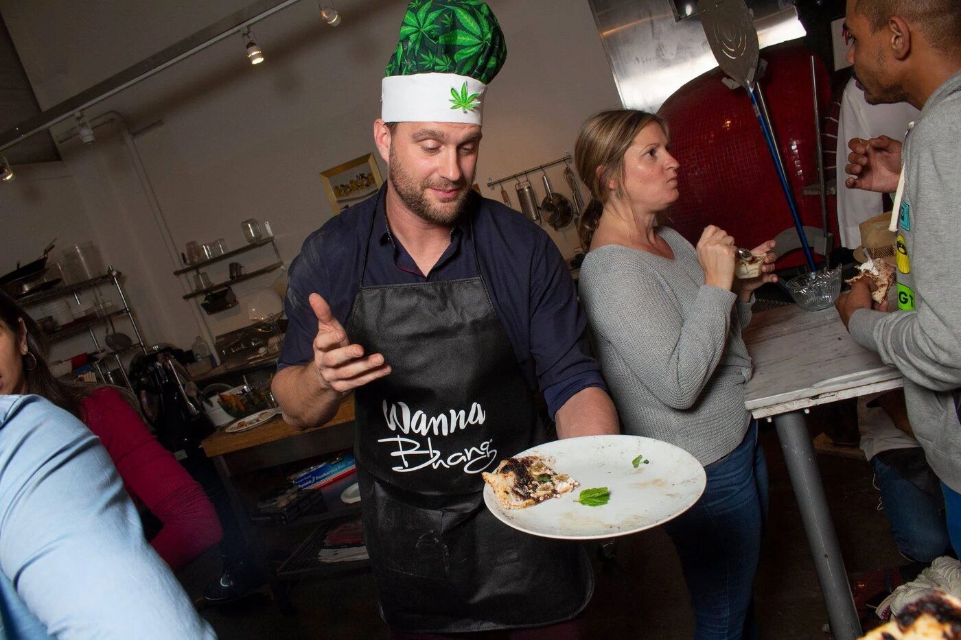 Chef in a cannabis-leaf hat and Wanna Bhang apron serving guests