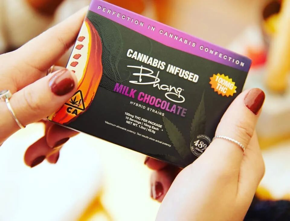 Hand holding a Bhang cannabis-infused milk chocolate package