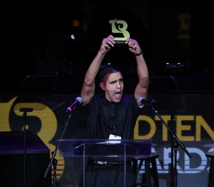 Winner raising a Budtender Awards trophy at the podium