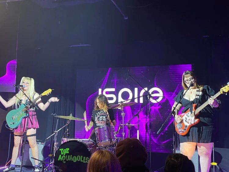 Band performing on stage in front of an Aspire backdrop
