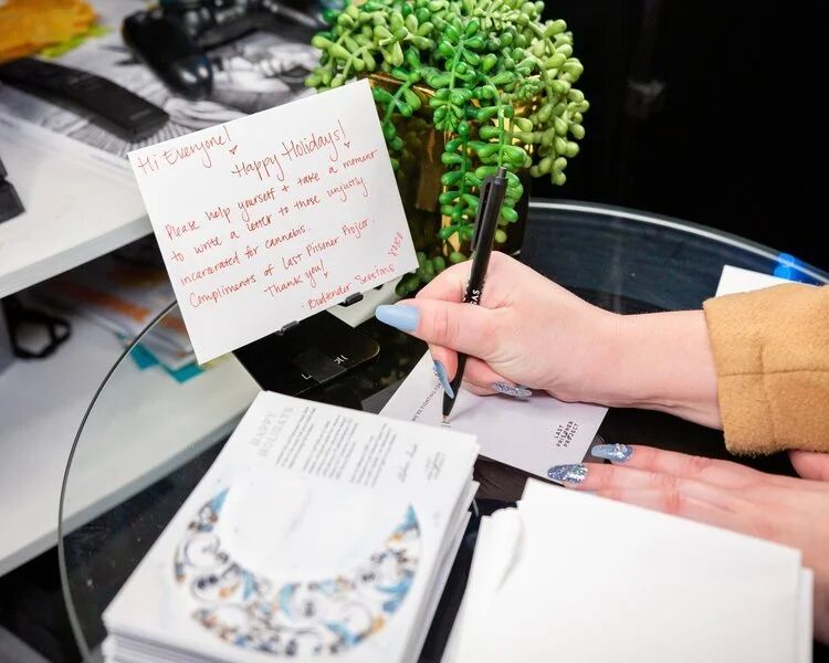 Guest writing a holiday card at a Budtender Sessions table