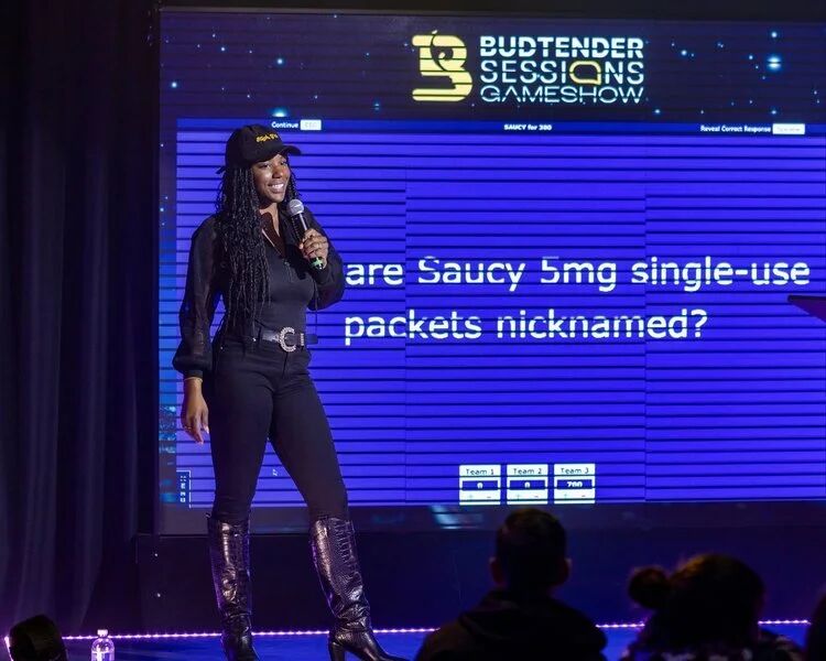 Budtender Sessions Gameshow host on stage asking what Saucy 5mg packets are nicknamed