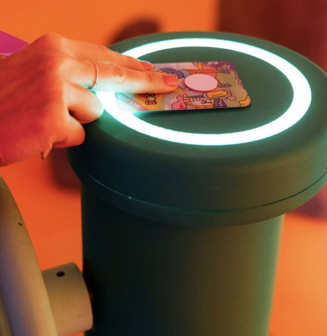Hand tapping an NFC card on a glowing reader at a DoodlePutt hole