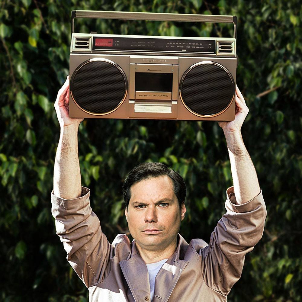 Michael Ian Black holding a boombox overhead, Say Anything parody