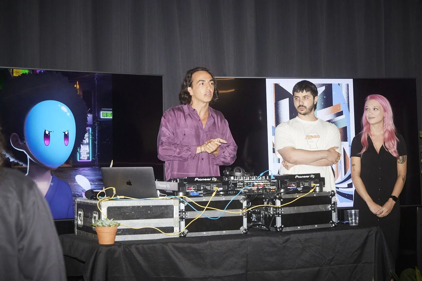 DJ booth beside digital art screens at Friends of OpenSea