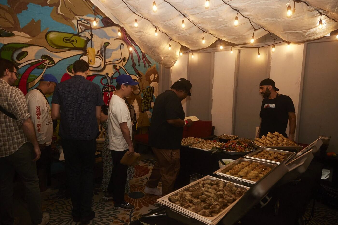 Guests at the catered food station under string lights