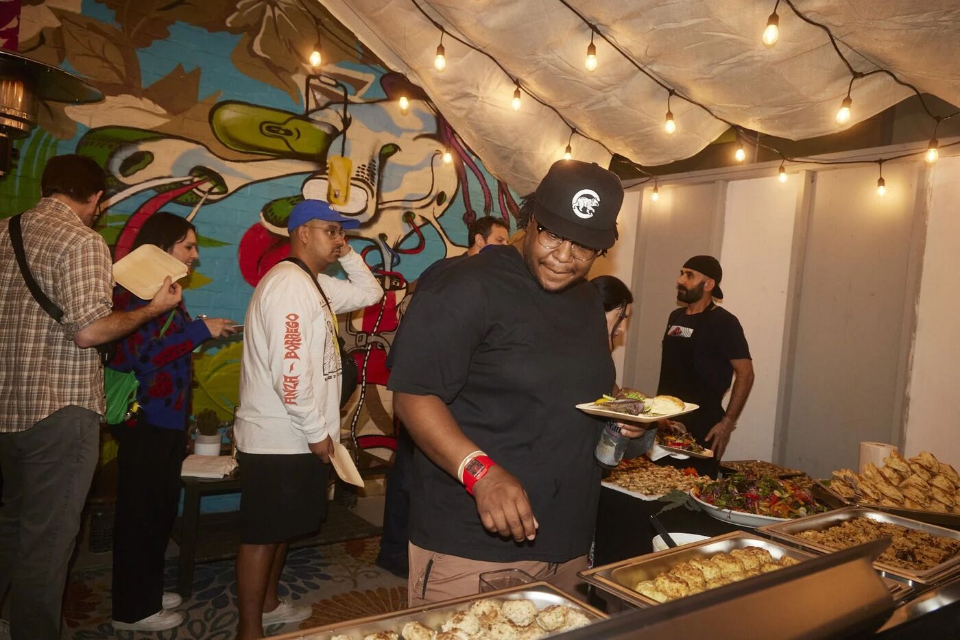 Guests serving themselves at the buffet beside a graffiti mural