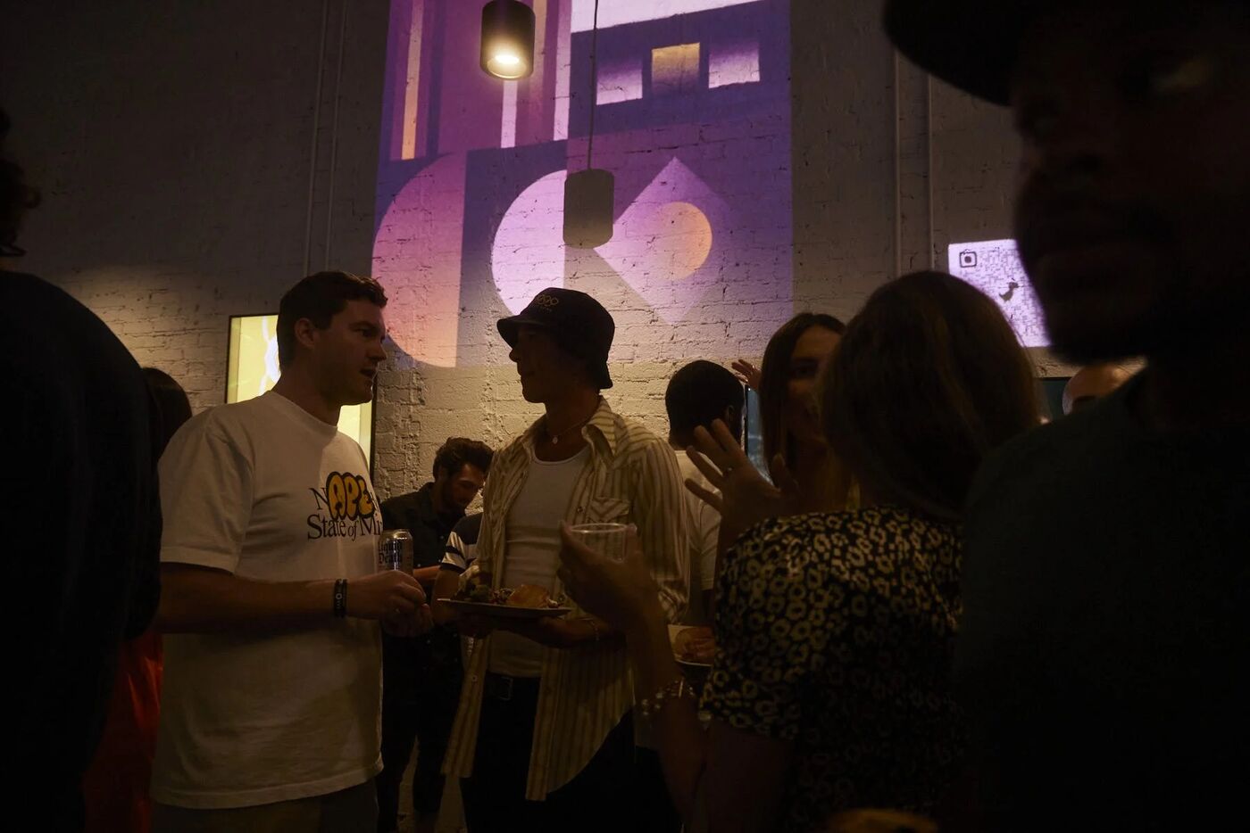 Guests in the dimly lit gallery under projected art