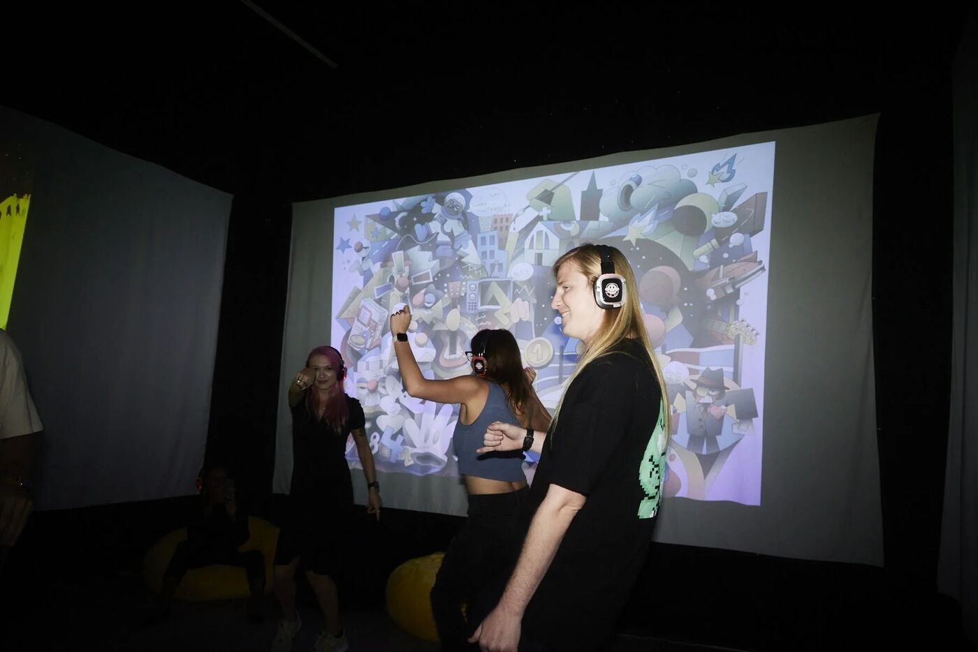 Guests in silent-disco headphones dancing in front of a projected artwork