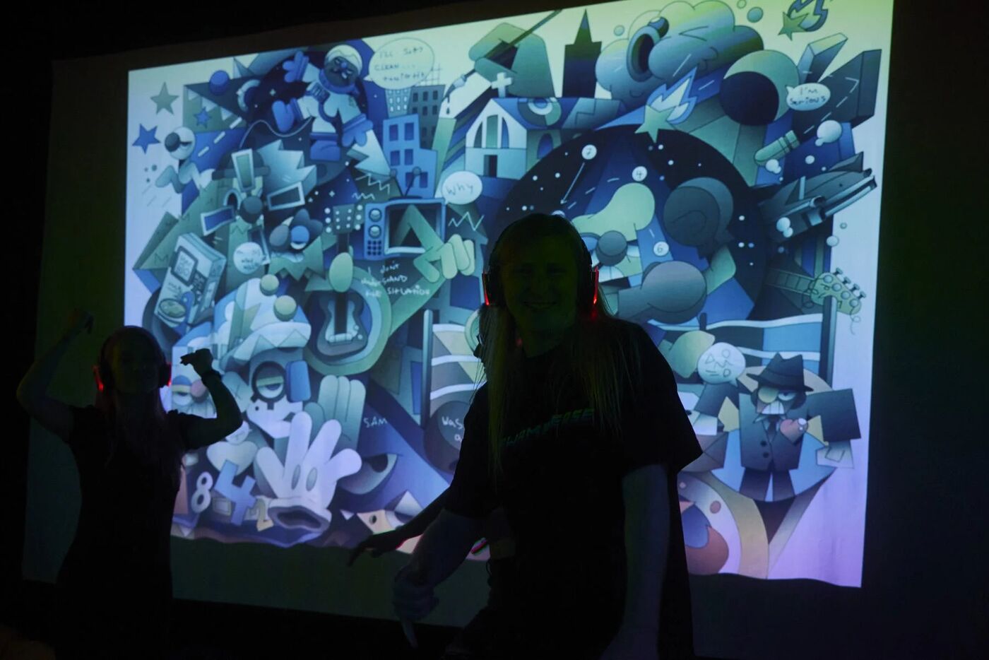 Silhouetted dancers in front of a large projected digital artwork