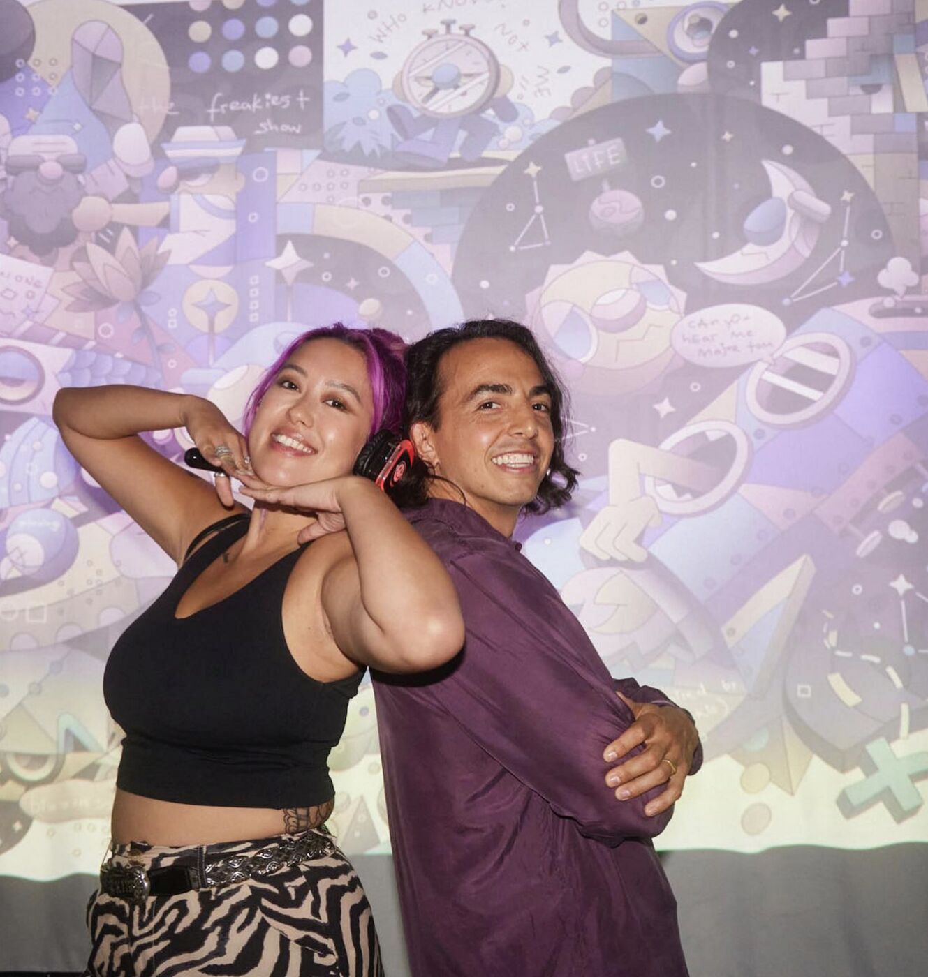 Two guests posing in front of projected artwork