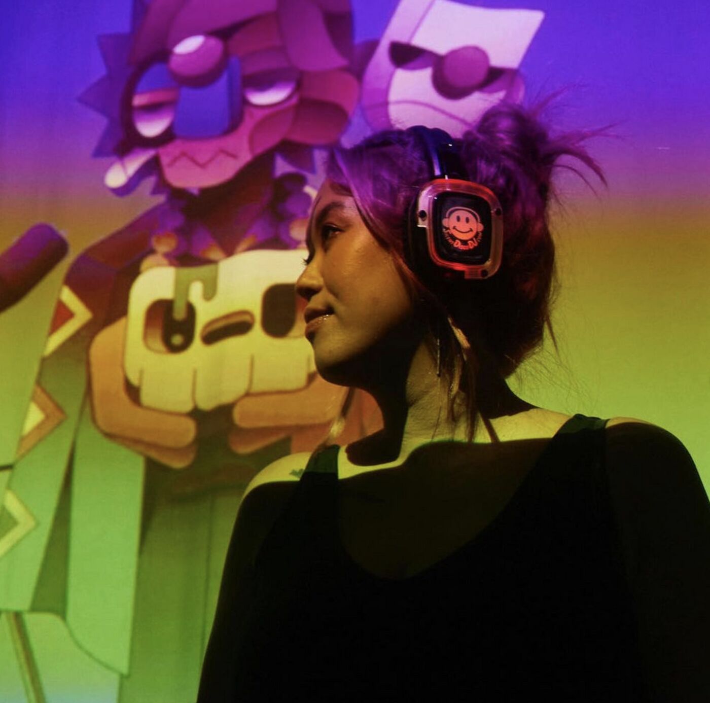 Guest in glowing headphones lit by colorful projected art