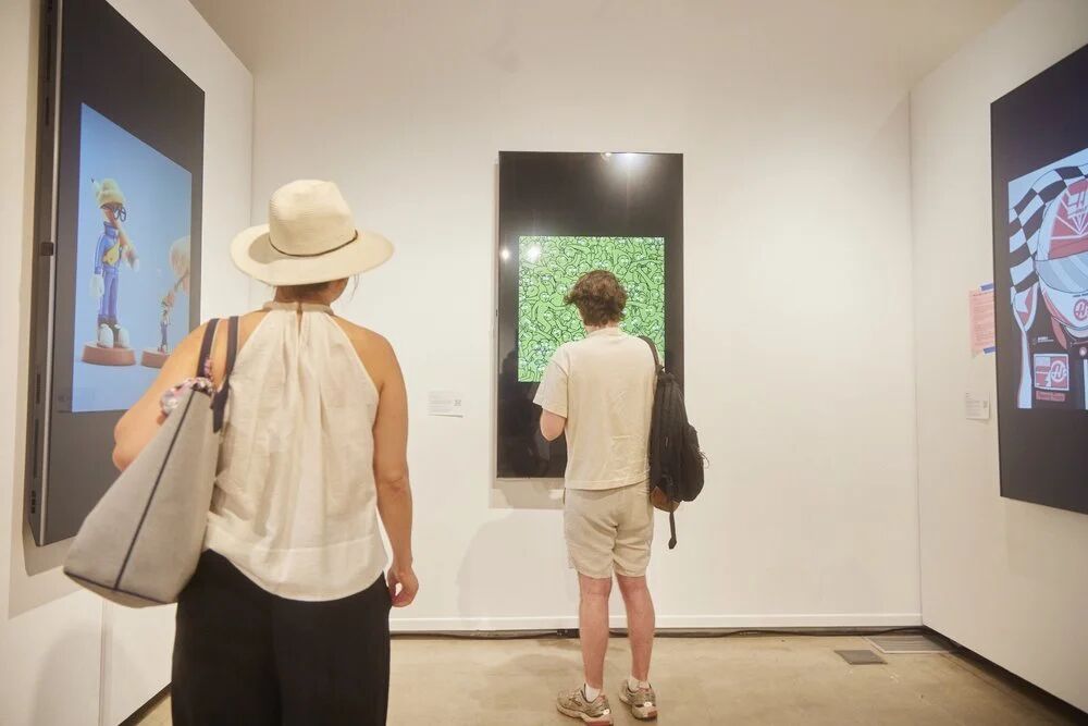 Visitors looking at digital art in the OpenSea gallery
