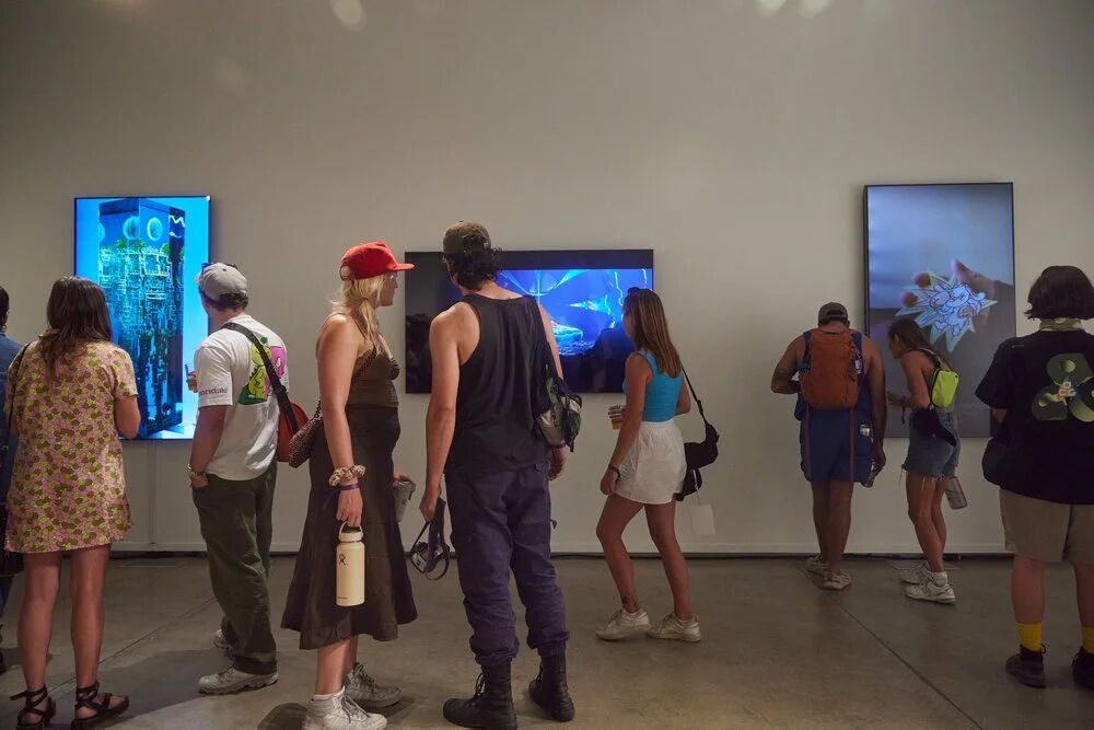 Guests walking past glowing digital art screens in the gallery