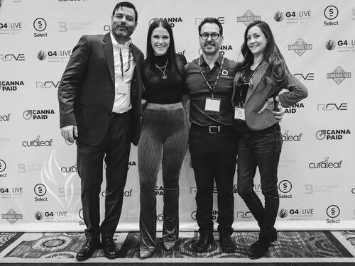 Black-and-white photo of four attendees at the G4 Live step-and-repeat