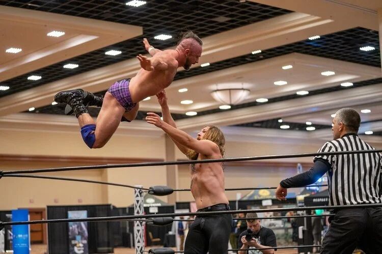 Wrestler leaping from the ropes during a wrestling match at G4 Live