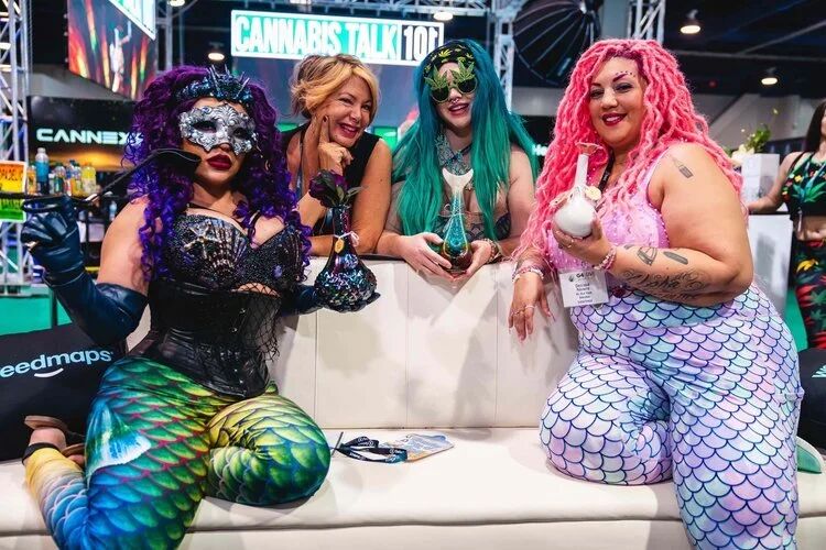 Costumed attendees posing on a couch at the Cannabis Talk 101 booth