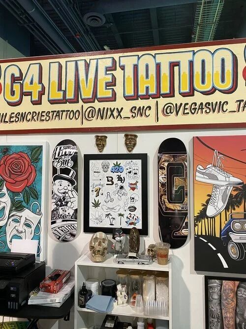 G4 Live Tattoo booth with artwork on skateboards and canvases