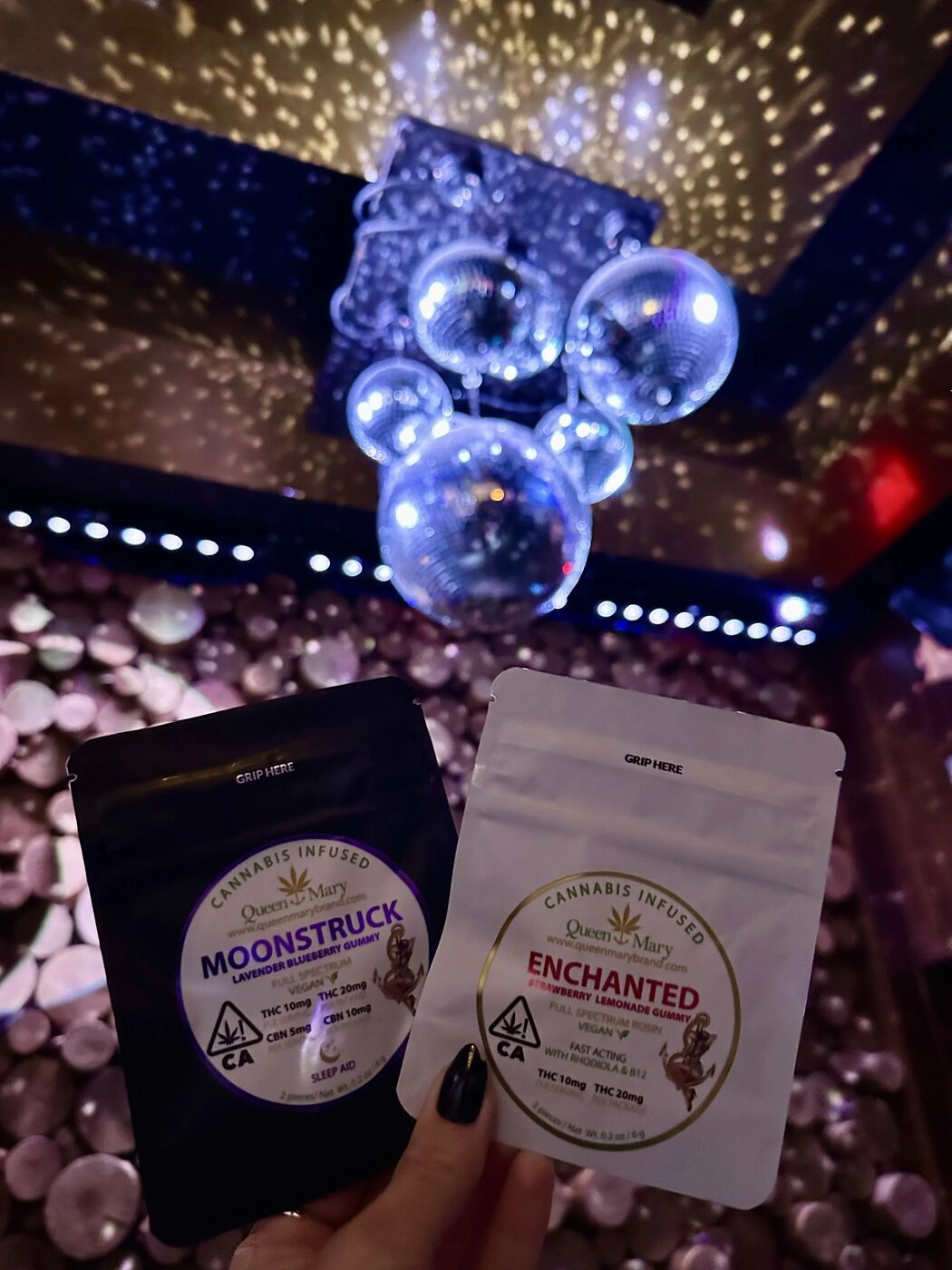 Hand holding Moonstruck and Enchanted cannabis pouches under disco balls