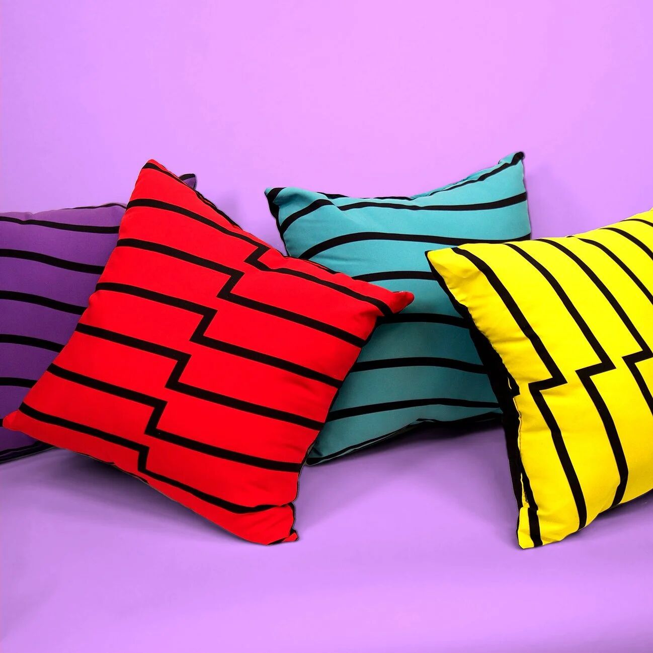 Red, teal and yellow Pop TV striped pillows on purple