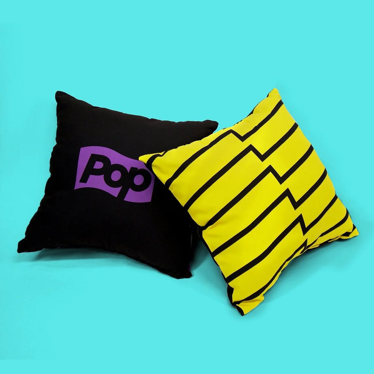 Pop TV logo pillow and yellow striped pillow on turquoise