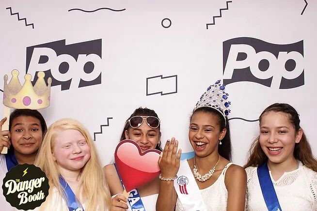 Party guests in tiaras and sashes at the Pop TV photo booth