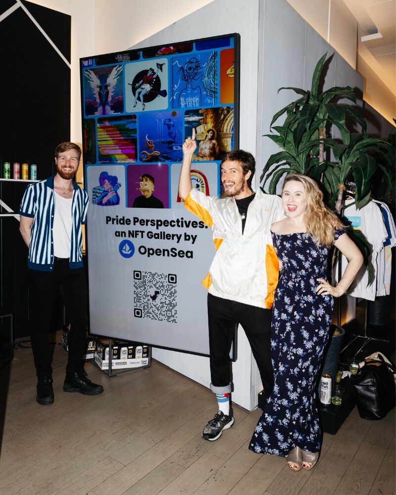 Guests posing beside the Pride Perspectives on NFT Gallery by OpenSea sign