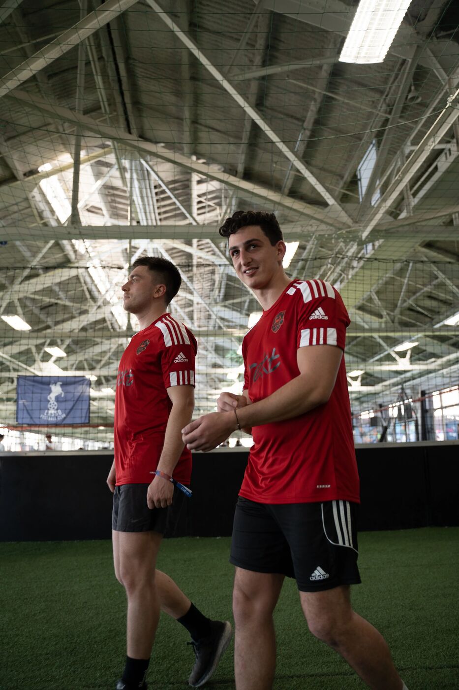 Two players in red kits walking off the pitch