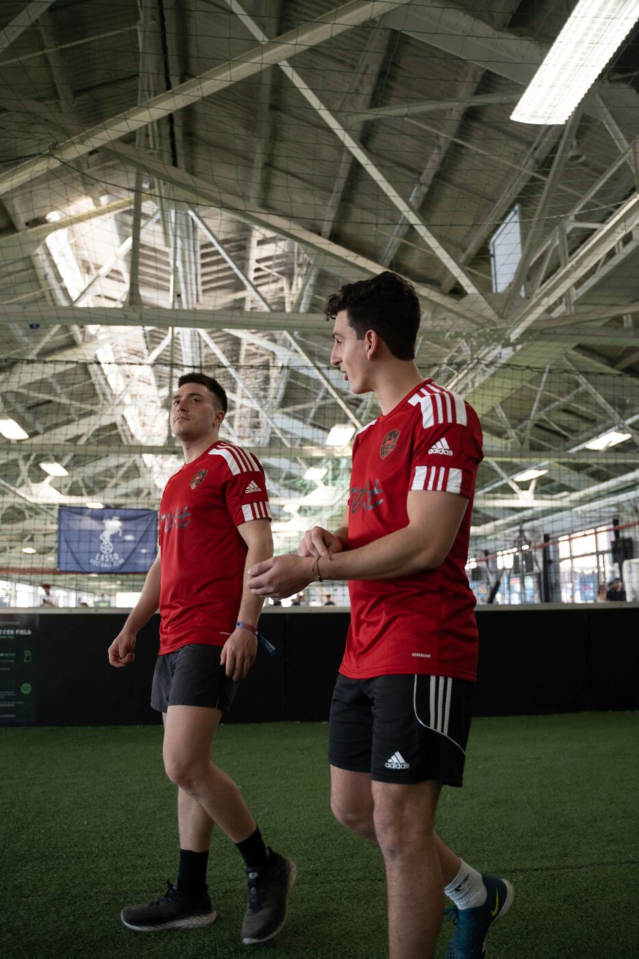 Two players in red kits talking on the field