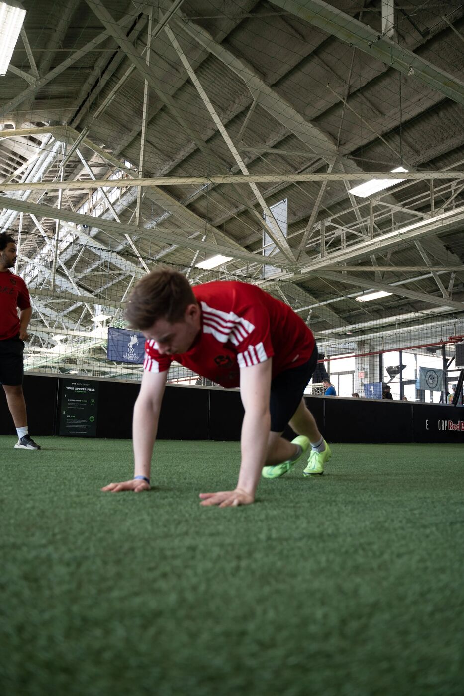 Player in a red kit stretching on the turf